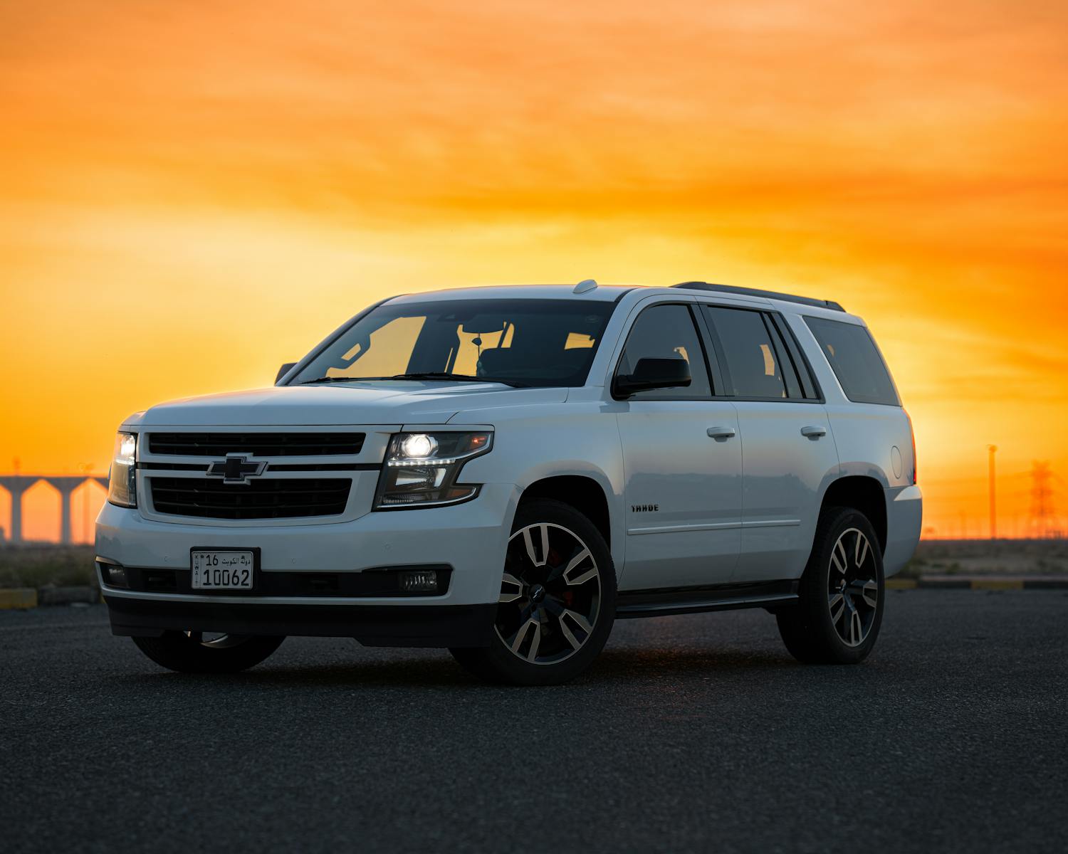 A white SUV parked on a deserted road with a vivid sunset in the background.